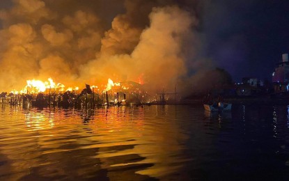 <p><strong>RAZED.</strong> A Philippine Coast Guard boat monitors a fire raging at the mouth of the Pasig River on Thursday (May 19, 2022) evening. No one was hurt in the fire. <em>(Photo courtesy of PCG)</em></p>