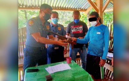 <p><strong>NPA REBEL YIELDS. </strong>New People’s Army fighter Rubin Enlab Daano (right), of the NPA’s Western Mindanao Regional Party Committee, hands over a shotgun following his surrender Tuesday (May 31, 2022) in Josefina, Zamboanga del Sur. Daano decided to surrender following intensified operations against communist rebels in the Zamboanga Peninsula. <em>(Photo courtesy of the Naval Forces Western Mindanao)</em></p>