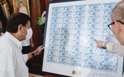 <p><strong>MODERN BANKNOTES.</strong> President Rodrigo Duterte (left) examines an uncut sheet of PHP1,000 polymer banknotes, with Bangko Sentral ng Pilipinas Governor Benjamin Diokno, at Malacañang Palace on April 6, 2022. The bills were first released in the National Capital Region on April 18.<em> (Presidential photo)</em></p>
