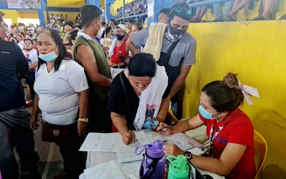 <p><strong>CASH AID.</strong> A beneficiary (center) signs a document to avail of the financial assistance from the Department of Social Welfare and Development in Davao Region Thursday (June 9, 2022) at the gymnasium of Barangay Tibanban in Governor Generoso, Davao Oriental. A total of 3,000 low-income residents received PHP3,000 each, sourced from the DSWD’s Assistance To Individuals in Crisis Situation. <em>(PNA photo by Che Palicte)</em></p>