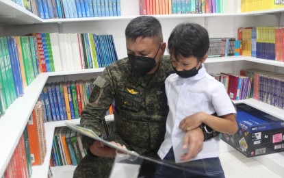 <p><strong>LEARNING HUB</strong>. Visayas Command chief Lt. Gen. Robert Dauz is seen reading a book for an elementary pupil inside a mini-library launched on Wednesday (June 8, 2022) at the Cambubho Integrated School in the hinterland of Danao City. Dauz on Thursday said Viscom will collaborate with the private sector in opening more learning hubs as a way to counter the communist terrorist group's propaganda. <em>(Photo courtesy of 3rd Civil Relations Group)</em></p>