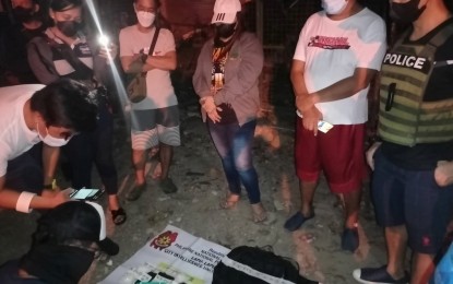 <p><strong>HIGH-VALUE TARGET</strong>. Suspect Eleonor Tagra Quistadio, a.k.a "Madam Aya" (in jacket and cap) looks on as police operatives do an on-site inventory of the illegal drugs seized from her during a sting operation in Barangay Pajo, Lapu-Lapu City on Monday night (June 14, 2022). The suspect, from Lianga, Surigao del Sur, yielded about four kilos of shabu worth P27.2 million. <em>(Photo by Jonalyn Jumabis)</em></p>