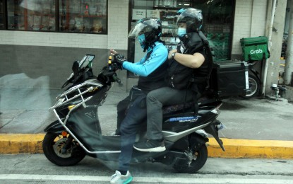 <p><strong>FOR HIRE</strong>. A motorcycle taxi rider carries a passenger in this undated photo. “Habal-habal” riders have been encouraged to join accredited ride-hailing operators. <em>(PNA file photo)</em></p>