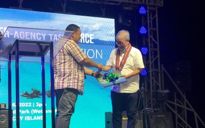 <p><strong>TURNOVER</strong>. Acting Environment Secretary Jim Sampulna (left), chair of the Boracay Inter-Agency Task Force (BIATF), turns over to Aklan Governor Florencio Miraflores the Boracay Coffee Table Book containing the transformation of the island during the culminating activity held Thursday (June 16, 2022) at the Balabag Wetland Park in Barangay Balabag, Boracay Island in Malay. The task force also turned over the management of the island to the Aklan and Malay local government units as its mandate will end on June 30. <em>(Photo courtesy of DENR Western Visayas)</em></p>