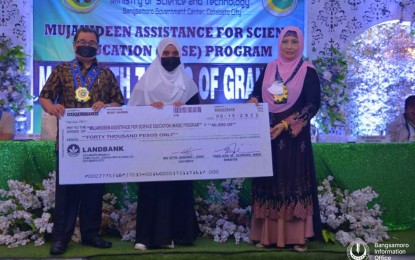 <p><strong>EDUCATION AID.</strong> A daughter of a Moro Islamic Liberation Front (MILF) mujahideen (center) poses with Bangsamoro Autonomous Region in Muslim Mindanao (BARMM) Education Minister Mohagher Iqbal (left) and Science and Technology Minister Aida Silongan with the replica of her PHP40,000 educational assistance from the government on Monday (June 20, 2022). At least 180 children of former MILF fighters benefited from the program. <em>(Photo courtesy of Bangsamoro Information Office–BARMM)</em></p>