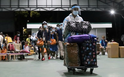 <p><strong>FRESH START.</strong> A BP2 staff member pushes a cart with luggage to be loaded on a bus that would take families who availed of the Balik Probinsya, Bagong Pag-Asa Program to their respective provinces and start life anew at BP2 Depot, Quezon Avenue corner Agham Road, Quezon City on May 28, 2021. The beneficiaries took a Covid-19 swab test which turned out negative before their departure to their provinces. <em>(PNA photo by Robert Oswald P. Alfiler)</em></p>