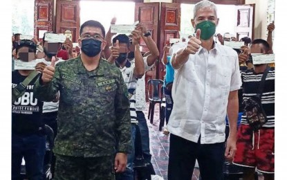 <p><strong>CASH AID</strong>. Negros Occidental Governor Eugenio Jose Lacson (right) and Brig. Gen. Inocencio Pasaporte, commander of the Philippine Army’s 303rd Infantry Brigade, with the former rebels who received cash assistance from the provincial government at the Provincial Capitol in Bacolod City on Wednesday (June 22, 2022). The beneficiaries, who were combatants and legal front members, received PHP30,000 each. <em>(Photo courtesy of 79th Infantry Battalion, Philippine Army)</em></p>