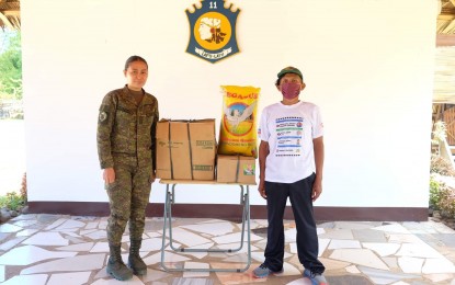 <p><strong>LIVELIHOOD ASSISTANCE.</strong> Lt. Pearl Lanuza, Civil-Military Operations officer of the Philippine Army's 11th Infantry Battalion, turns over to former rebel Reynaldo Paculanang P8,000 worth of groceries to start a "sari-sari" store business on Friday (June 24, 2022). The business kit was livelihood assistance from the Department of Trade and Industry aimed at helping surrendered rebels start a new life. <em>(Photo by Judy Flores Partlow)</em></p>