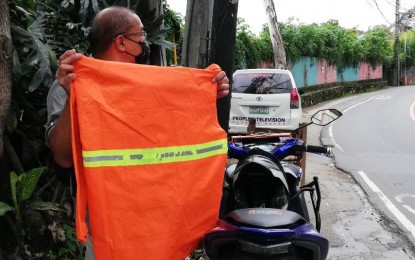 <p><strong>FOR VISIBILITY</strong>. A motorcycle rider in Baguio City shows a reflectorized raincoat that he uses for visibility, as afternoon rains and fog are common in Baguio and Benguet in this undated photo. Benguet Governor Melchor Diclas has suspended the ordinance mandating the use of visibility vests so inputs from the community could be included in the measure. <em>(PNA photo by Liza T. Agoot)</em></p>