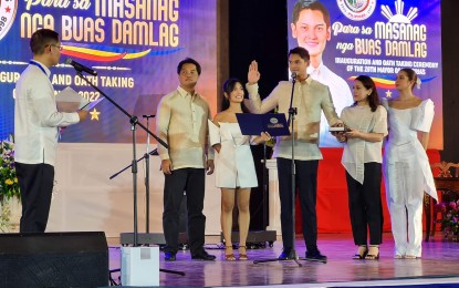 <p><strong>NEWCOMER</strong>. Former actor Javier Miguel Benitez, 27, takes his oath as the youngest mayor of Victorias City, Negros Occidental before his uncle, Third District Rep. Jose Francisco Benitez, in rites held at the northern city’s Sports and Amusement Center on Wednesday afternoon (June 29, 2022). Joining him were his father, the new Bacolod City Mayor Alfredo Benitez (2nd from left), mother Nikki (2nd from right), sister Bettina (center), and girlfriend, actress Sue Ramirez. <em>(Photo courtesy of Erwin P. Nicavera)</em></p>