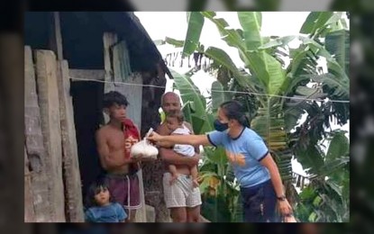 <p><strong>GIVING BACK.</strong> A police officer gives a food pack to a family belonging to the Agta-Tabangnon tribe in Tiwi town in Albay on Monday (July 4, 2022). The Police Regional Office 5 said the distribution of food packs to families belonging to the Agta-Tabangnon tribe in the town is part of the observance of the 27th Police Community Relations month. <em>(Photo courtesy of PRO-5 Facebook page)</em></p>