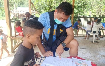 <p><strong>EXPANDING ROLES.</strong> A police officer in this undated photo assists a boy in answering his modules. More than law enforcement, the police are taking the roles of community leaders to develop good relations with its host communities through its Revitalized Pulis sa Barangay Program.<em> (Photo courtesy of PRO-11)<br /></em></p>