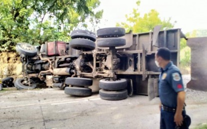 <p><strong>WAYWARD TRUCK</strong>. A policeman guards the dump truck that turned on its side after hitting motorcycle riders on Friday afternoon (July 15, 2022) in San Carlos City, Negros Occidental. Killed in the accident was Lt. Col. Ruben Verbo Jr., the police chief of Guihulngan City, Negros Oriental, while Col. Germano Mallari, the provincial police director of Negros Oriental, and three others sustained injuries. <em>(Photo courtesy of the San Carlos City Police Station)</em></p>
