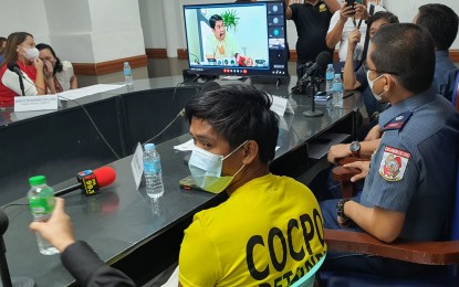 <p><strong>CONMAN.</strong> Officials of the Cagayan de Oro City Police Office present to reporters Jhon Carl Mendoza (center) alias Jay Lagrimas, the alleged ringleader of the 'pay-for-ayuda' syndicate victimizing Department of Social Welfare and Development (DSWD) program beneficiaries. DSWD-10 Director Mari-flor Dollaga (upper right) also presented the suspect before DSWD chief Erwin Tulfo via online video conferencing Wednesday (July 20, 2022). <em>(PNA photo by Nef Luczon)</em></p>