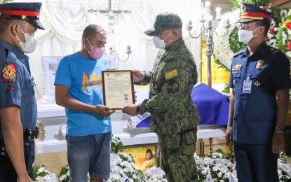 <p><strong>HERO COP. </strong>Lt. Gen. Jose Chiquito Malayo, commander of the PNP's Area Police Command-Visayas, confers the PNP Distinguished Conduct Medal (Medalya ng Kadakilaan) to the bereaved kin of Pat. Mark Monge during a visit to his wake on Monday (July 18, 2022). Monge was killed in an ensuing encounter from an ambush by communist rebels during a humanitarian activity in Samar last July 16. <em>(Photo courtesy of PNP)</em></p>