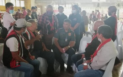 <p><strong>INITIAL TALKS</strong>. Kalinga Governor James Edduba (2nd from right, seated) and Mountain Province Governor Bonifacio Lacwasan Jr. (2nd from left, seated), along with the police and some elders in both provinces, meet for the first time in Sagada, Mountain Province on July 1, 2022 for a short exploratory talk on how to end the conflict between the Betwagan tribe of Sadanga, Mountain Province, and the Butbut tribe of Kalinga. Officials of both provinces agree that the traditional way of settling disputes might help end the tribal war that began in the 1990s. <em>(PNA photo by Liza T. Agoot)</em></p>