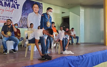 <p><strong>SHOE FITTING.</strong> Senator Christopher Lawrence Go (center) watches two residents of Manay, Davao Oriental as they fit the shoes given by his office on Thursday (July 28, 2022). Go witnessed the distribution of PHP11 million in cash assistance from the DSWD 11 (Davao region) to 2,200 beneficiaries in the town. <em>(PNA photo by Che Palicte)</em></p>