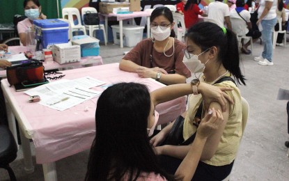 <p><strong>PROTECTION.</strong> Celine Marylle Vidanes, 14, receives her first booster shot against Covid-19 at a mall in Dasmariñas City, Cavite on July 28, 2022. As of August 14, at least 17 million have the additional shot from among the 72.1 million who are fully vaccinated, based on Department of Health data.<em> (PNA photo by Gil Calinga)</em></p>