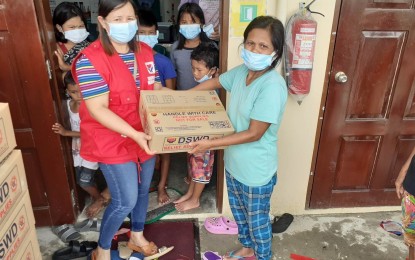 <p><strong>RELIEF</strong>. An employee of the Department of Social Welfare and Development (DSWD) gives a family food pack to one of the households affected by flood in San Jose de Buenavista, Antique on Saturday (July 30, 2022). Provincial Disaster Risk Reduction and Management Officer Broderick Train said in an interview Sunday that families who evacuated have returned home as the weather improved. <em>(PNA photo courtesy of DSWD-Antique)</em></p>