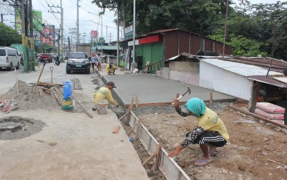 <p><strong>HEAT BREAKS</strong>. A construction worker is seen preparing to cement a sidewalk along a highway in Dasmarinas City, Cavite on Aug. 11, 2022. A lawmaker has proposed to give special breaks to workers during times of intense heat. <em>(PNA file photo)</em></p>