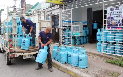 <p><strong>PRICE CUT.</strong> Workers unload tanks of liquefied petroleum gas (LPG) from a delivery truck along Congressional Road in Barangay H2, Dasmariñas City, Cavite in this undated photo. Prices of LPG go down by at least PHP6 per kilogram this month. <em>(PNA photo by Gil Calinga)</em></p>