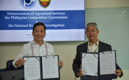 <p><strong>PCC-NBI TIE-UP.</strong> Philippine Competition Commission officer-in-charge Johannes Bernabe (left) and National Bureau of Investigation Director Medardo de Lemos (right) sign the memorandum of agreement between the two agencies at the PCC office in Quezon City Wednesday (Aug. 17, 2022). This partnership aims to strengthen PCC's enforcement capacity. <em>(Photo courtesy of PCC)</em></p>