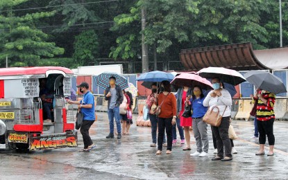 <p><strong>RAINY TUESDAY. </strong>Commuters queue while waiting for jeepneys and buses on their way to work at the corner of Elliptical Road and North Avenue in Quezon City amid light rains on Aug. 23, 2022. Metro Manila and the rest of the country will have isolated rain showers caused by localized thunderstorms, according to weather bureau PAGASA. (PNA file photo by Joey O. Razon)</p>