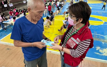 <p><strong>PAYOUT.</strong> DSWD-7 OIC regional director Shalaine Lucero hands out the cash assistance in this undated photo to a grandfather representing a learner who qualified for the government's cash assistance program. Some 5,000 learners in Central Visayas are expecting to receive their educational assistance during the second payout on Saturday (Aug. 26, 2022). <em>(Photo courtesy of DSWD Region 7)</em></p>