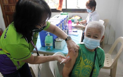 <p>A senior citizen receives her Covid-19 vaccine. <em>(PNA photo by Gil Calinga)</em></p>