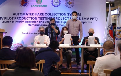 <p><strong>MOA SIGNING</strong>. Landbank Card and Electronic Banking Group head Randy Montesa (seated left), Land Transportation Franchising and Regulatory Board Chair Cheloy Garafil (seated center), and PM Jeepney Drivers and Operators Services, Inc. chair Roberto Martin (seated right) show to the media the signed copies of a memorandum of agreement (MOA) on the use of EMV-enabled contactless card in public transport, at the Parañaque Integrated Terminal Exchange (PITX) on Thursday (Sept. 1, 2022). A total of 150 modern jeepneys will initially be part of the pilot program, which will be used to develop national standards for an automated fare collection system. <em>(PNA photo by Jesus Escaros Jr.)</em></p>