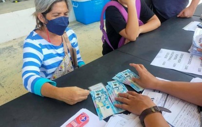 <p><strong>ASSISTANCE.</strong> A senior citizen from Iloilo City receives financial assistance on behalf of her three grandchildren during the payout on Aug. 27, 2022. The Department of Social Welfare and Development targets to serve 11,751 students-in-crisis in Western Visayas during the third payout of the educational assistance that will be held in 30 venues on Saturday. <em>(PNA photo courtesy of DSWD Western Visayas FB page)</em></p>