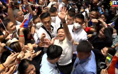 <p><strong>APPRECIATION.</strong> President Ferdinand “Bongbong” Marcos Jr. waves to the about 1,5000 Filipinos at the Ho Bee Auditorium of the National University of Singapore to kick off his visit on Tuesday (Sept. 6, 2022). Marcos thanked the Filipino workers for their overwhelming support during the last May 9 national elections. <em>(Screengrab from RTVM)</em></p>