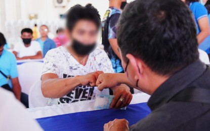 <p><strong>CASH AID.</strong> A former New People's Army (NPA) rebels fist bumps with a government worker after receiving PHP23,000 financial aid on Monday (Sept. 5, 2022). The former rebels earlier took part in interventions from government agencies that include technical training, education, and practical skills, among others.<em> (Photo courtesy of Davao Oriental PIO)</em></p>