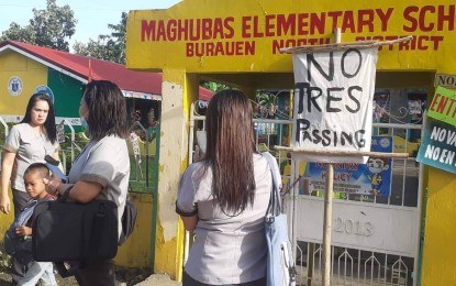 <p><strong>NO TRESPASSING</strong>. Teachers and learners wait outside the campus of a public elementary school in Burauen, Leyte after a claimant padlocked the gate early Wednesday (Sept. 7, 2022). The school opened after a few hours with the help of local officials and police. <em>(Photo courtesy of Gil Tamayo)</em></p>