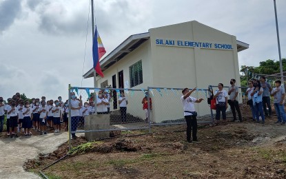 <p><strong>NEW SCHOOL</strong>. Learners together with officials of the province of Pangasinan and the Department of Education sing the national anthem during the inauguration of the Silaki Elementary School. The islet of Sitio Silaki is part of mainland Barangay Binabalian, so the learners used to ride a motorboat to and from Binabalian Elementary School traversing rough waters when it is raining, thus entering the classroom soaked in wet uniforms. <em>(Photo by Liwayway Yparraguirre)</em></p>