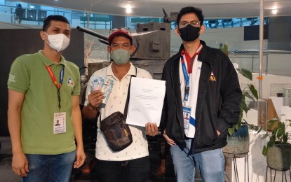 <p><strong>ASSISTANCE.</strong> Jessie Cruz (center), a resident of Mariveles, Bataan, and a former overseas Filipino worker, shows the cash assistance that he received from the Department of Labor and Employment (DOLE) during the distribution at the Capitol compound in Balanga City, Bataan on Wednesday (Sept. 14, 2022). This is under the DOLE's Abot Kamay ang Pagtulong (AKAP) program that gives one-time financial assistance of PHP10,000 to OFWs who lost their employment amid the pandemic.<em> (Photo courtesy of OWWA Region 3)</em></p>