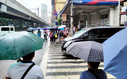 <p><strong>WET COMMUTE.</strong> Commuters shield themselves from the rain using umbrella while waiting to cross the pedestrian lane along Pedro Gil St. in Manila on Sept. 19, 2022. A huge part of the country will experience rain showers caused by the low pressure area which will be named "Egay" once it enters the Philippine Area of Responsibility, the weather bureau said. <em>(PNA photo by Alfred Frias)</em></p>