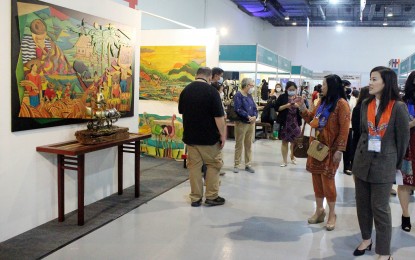 <p>DOT Undersecretary, Shereen Gail Yu-Pamintuan (right) looks at the exhibit painting display during the first leg of the DOT-DOLE job fair at the SMX Convention Center Manila in the Mall of Asia Complex in Pasay City last year. <em>(PNA photo by Gil Calinga)</em></p>