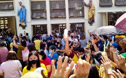 <p><strong>FACE MASKS ON.</strong> A church volunteer sprinkles holy water on devotees outside the Quiapo Church in Manila in this photo taken Sept. 23, 2022. The Archdiocese of Manila is encouraging parishioners to continue wearing face masks inside churches in compassionate regard to the elderly and the vulnerable. <em>(PNA photo by Alfred Frias)</em></p>