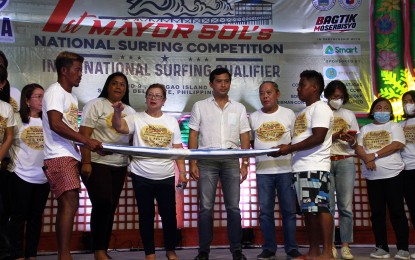 <p><strong>MAJOR ATTRACTION.</strong> Department of Tourism Undersecretary Shahlimar Hofer Tamano (center) joins Mayor Sol Matugas (left) and former Surigao del Norte Gov. Francisco Matugas (right) during the ceremonial breaking of a surfboard on Wednesday (Sept. 28, 2022), one of the major highlights of the 1st Mayor Sol’s National Surfing Competition in Gen. Luna, Siargao Island. Tamano noted that surfing has, for years, been the major attraction for local and foreign tourists on the island. <em>(PNA photo by Alexander Lopez)</em></p>