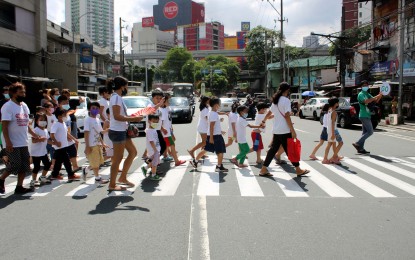 <p>Children and their guardians walk along the pedestrian lane. <em>(PNA photo by Robert Oswald Alfiler)</em></p>
