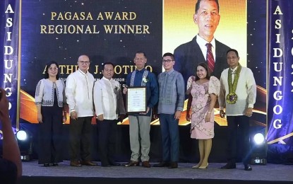 <p><strong>RECOGNIZED</strong>. Arthur J. Cotimo (center), Education Program Supervisor of the Schools Division Office of the Guimaras Learning Resource Management Section of the Department of Education, receives his award as one of the Pag-asa Awardees for the Honor and Awards Program of the Civil Service Commission on Sept. 28, 2022. He said on Tuesday (Oct. 4, 2022) that the recognition inspired him to come up with more learning resources. <em>(Photo screen grab from CSC live streaming)</em></p>