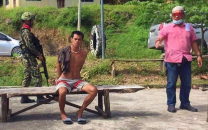 <p class="p1"><span class="s1"><strong>CAUGHT, HANDCUFFED.</strong> Police officers keep an eye on Mubarak Bangon of Barangay Bitu, Datu Odin Sinsuat, Maguindanao after his arrest with the help of local officials on Tuesday (Oct. 4, 2022). He has 10 counts of warrants for illegal possession of firearms.<em> (Photo courtesy of CIDG-BARMM)</em></span></p>