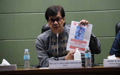 <p><strong>'PERSON OF INTEREST'.</strong> DILG Secretary Benjamin Abalos Jr. shows a picture of one of the suspects in the killing of veteran broadcaster Percy Lapid in a presser at the National Capital Region Police Office on Friday (Oct. 7, 2022). The reward for any information on the killing of Lapid has also increased to PHP1.5 million. <em>(PNA photo by Lloyd Caliwan)</em></p>