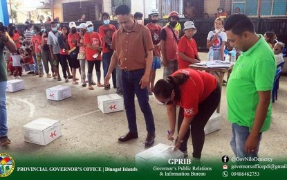 <p><strong>AID TO DISTRESSED FAMILIES.</strong> Dinagat Islands Governor Nilo Demerey Jr. (3rd from right) joins the staff from the Philippine National Red Cross in the distribution of kitchen sets and food aid to the residents of Barangay Sta. Cruz in San Jose town on Tuesday (Oct. 11, 2022). The two-day distribution activity culminated Wednesday, benefitted 591 families in three barangays hit by Typhoon Odette in December last year. <em>(Photo courtesy of Dinagat Islands PIO)</em></p>