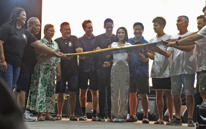 <p><strong>INTERNATIONAL SURFING CUP.</strong> Tourism Secretary Christina Frasco (center) leads the ceremonial breaking of a surfboard to open the 26th Siargao International Surfing Competition in Gen. Luna town on Saturday night (Oct. 15, 2022). Frasco said the national government will give its support to the efforts to help Siargao Island recover from the effects of the pandemic and fully revive the island’s tourism industry. <em>(PNA photo by Alexander Lopez)</em></p>