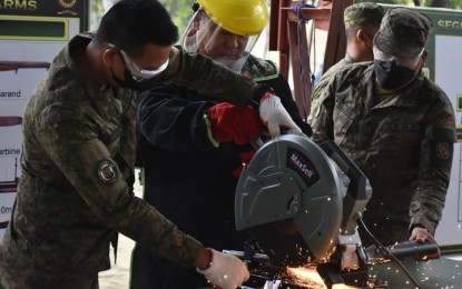 <p><strong>DEMILITARIZED.</strong> Assisted by servicemen, Brig. Gen. Arturo Rojas, acting commander of the Western Mindanao Command (center) cuts into pieces a rifle during the demilitarization of firearms at Camp Gen. Arturo Enrile in Zamboanga City  Tuesday (Oct. 18, 2022). After cutting into pieces, the parts of firearms were burned to ensure that none of the weapons’ components would be recycled.<em> (Photo courtesy of Westmincom)</em></p>