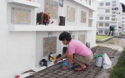 <p>A woman offers flowers at the tomb of her departed loved one. <em>(PNA photo by Gil Calinga)</em></p>