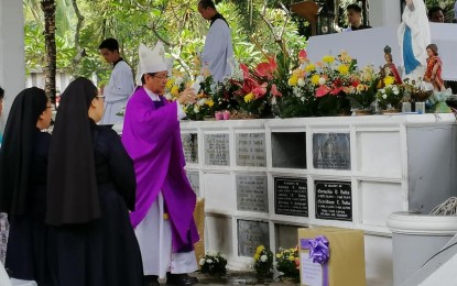<p><strong>VAX CARD REQUIRED</strong>. Dumaguete Bishop Julito Cortes blesses the tombs at the Roman Catholic Church cemetery in this undated photo. The city police said they are implementing a "no vax card, no entry" policy this year at the different cemeteries to prevent the spread of Covid-19. <em>(PNA file photo by Judy Flores Partlow)</em></p>