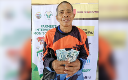 <p><strong>FARMING SUPPORT.</strong> Isaias Israel, 62, from Barangay Panamaon, Loreto, Dinagat Islands, shows the PHP5,000 cash aid he received through the Rice Competitiveness Enhancement Fund-Rice Farmers' Financial Assistance (RCEF-RFFA) program of the Department of Agriculture (DA) on Wednesday (Oct. 25, 2022). The DA in Caraga Region is currently conducting the Oct. 24-28 cash aid distribution to 1,752 rice farmer-beneficiaries in the province. <em>(Photo courtesy of DA-13)</em></p>